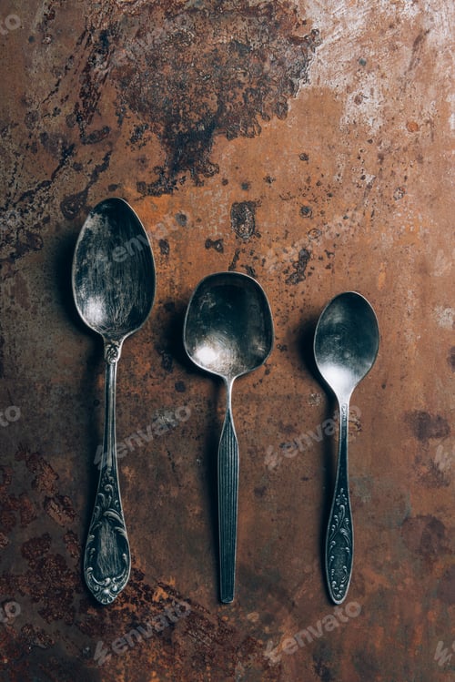Preview: elevated view of three silver spoons on grungy table