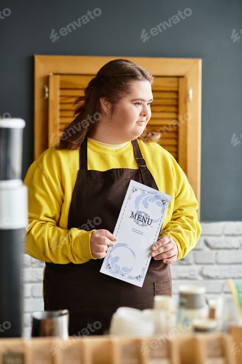Preview: Young woman with Down syndrome confidently holds a menu in a bustling cafe setting
