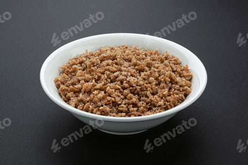 Preview: Bowl of buckwheat flakes on black background