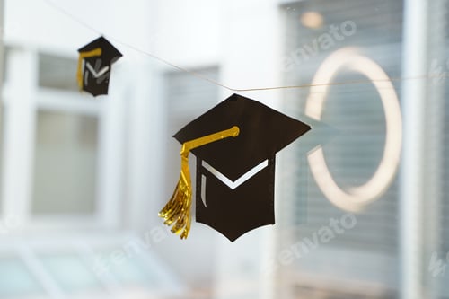 Preview: Black graduation cap with yellow brim with blurred classroom on the horizon