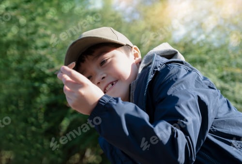 Preview: Happy child boy playing outdoors in the garden with bright light on summer, kid playing in the park