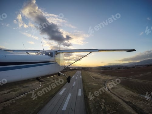 Preview: Small airplane taking off from a runway during a vibrant evening before sunset