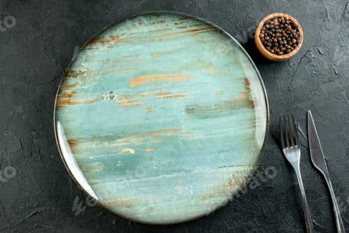 Preview: top view round platter dinner knife and fork black pepper in bowl on black table