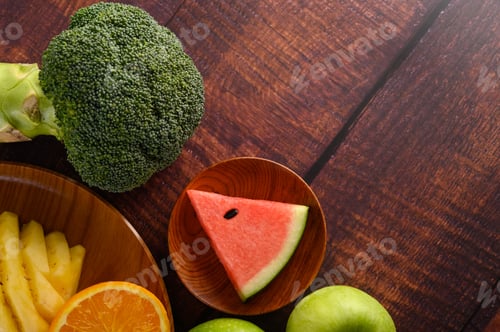 Preview: Cut watermelons, oranges and pineapples with apples and Broccoli on a wooden plate.