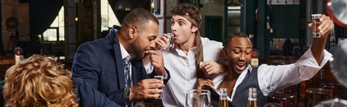 Preview: banner of funny and drunk multicultural men in formal wear drinking tequila in bar after work