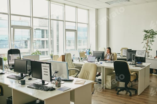 Preview: Young elegant businesswoman sitting by desk in the corner of modern office