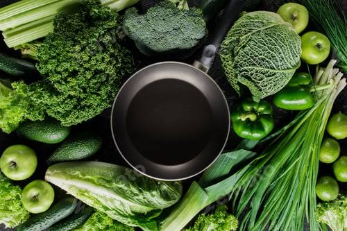 Vista previa: top view of frying pan between green vegetables, healthy eating concept