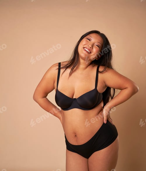Preview: Full length of cheerful Chinese woman wearing underwear in studio shot
