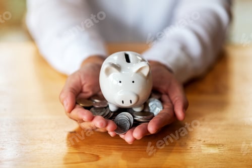 Preview: a woman holding piggy bank and coins in hands on the table