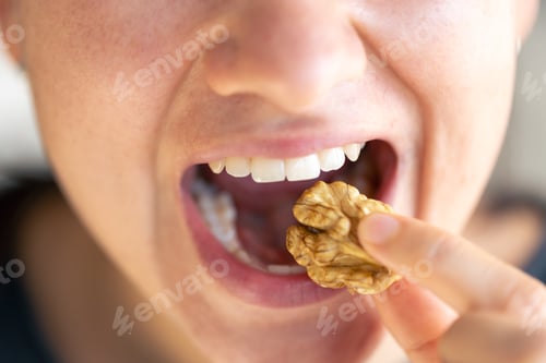 Preview: Detailed shot of a woman bites walnut.