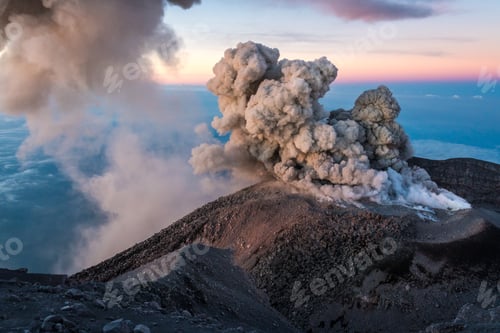 Preview: Scenic view of smoke going out of a rocky volcanic mountain during sunset