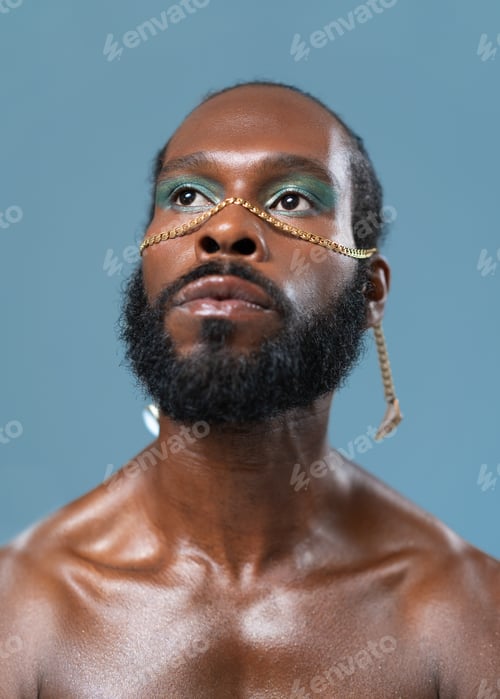 Preview: Thoughtful bearded gay man with makeup on blue background