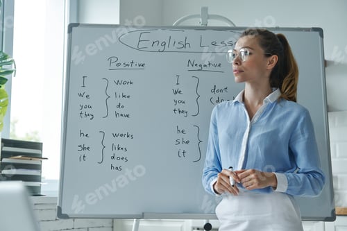Preview: Thoughtful young woman standing near the whiteboard at the classroom