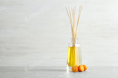 Preview: Aromatic reed freshener and kumquat on table against light background. Space for text