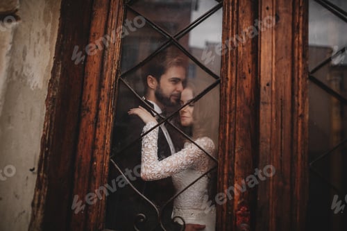 Preview: Young stylish newlyweds are hugging behind old rustic wooden door. wedding day.