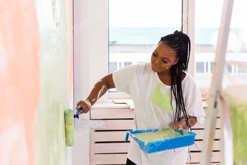 Preview: Happy African American woman painting wall in her new apartment. Renovation, redecoration and repair