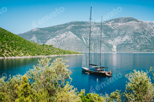 Preview: Summer vacation in Greece. Luxury black private yacht at anchor in beautiful sea lagoon. Ithaka