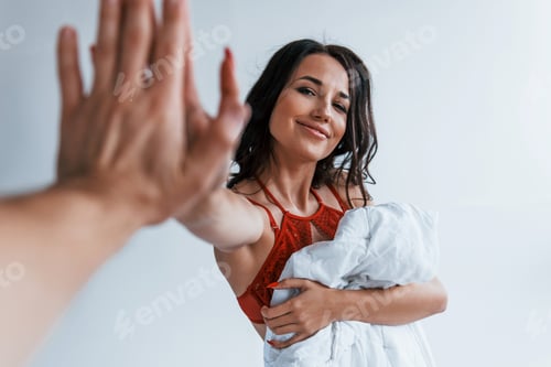 Preview: Positive beautiful young brunette in underwear in white room gives high five to the other person