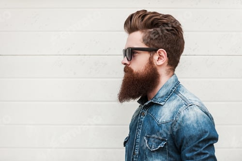 Preview: Perfect style. Side view of young bearded man in eyewear looking away while standing outdoors