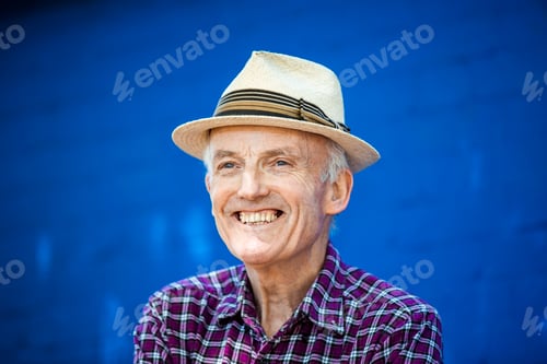 Preview: Portrait of happy senior man, blue brick wall in background