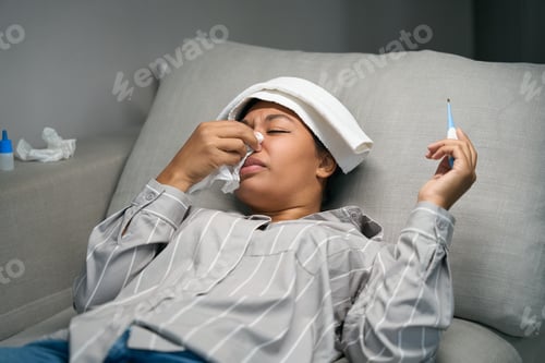 Preview: African american woman lies on the couch with runny nose