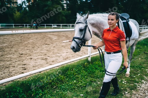 Preview: Caucasian girl jockey 20s leads breed animal for dressage outdoors