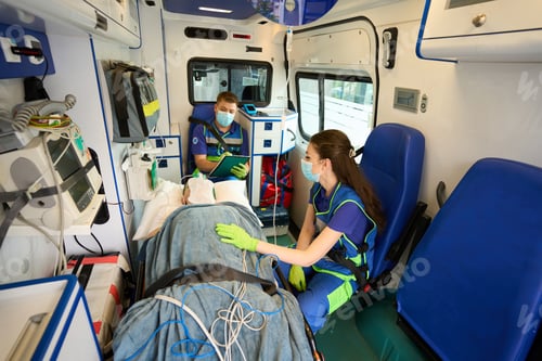 Preview: Doctors of mobile team transport patient in oxygen mask in ambulance