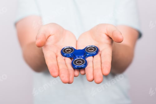 Preview: young man holding with a fidget spinner close up