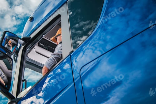 Preview: Truck Driver Sitting in Drivers Seat of a Blue Semi Truck