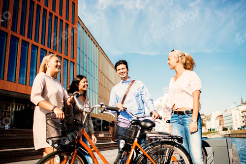 Preview: Happy friends with bicycles standing outside concert hall in Malmo Live