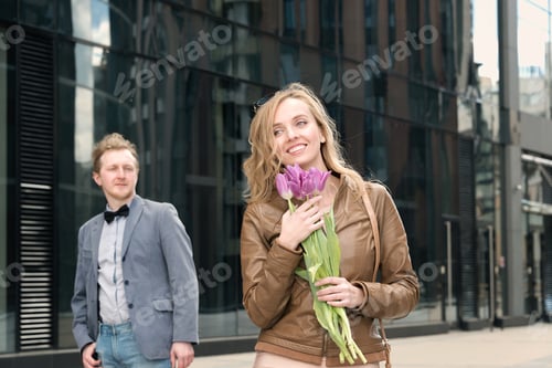 Preview: Woman with Flowers Outside Urban Building with Man