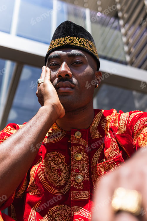 Preview: Thoughtful black man in traditional clothes and headdress near building
