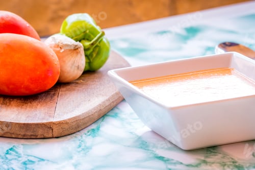 Preview: White plate of Andalusian gazpacho with the ingredients aside.