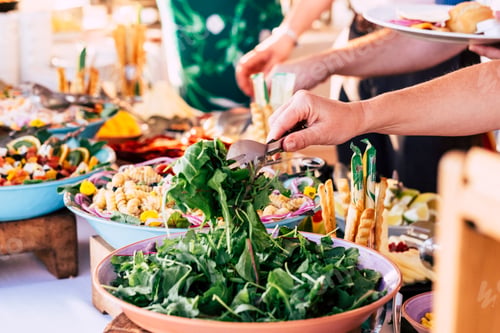 Preview: close up of view of table full of food with someone taking vegetables of the table to celebrate