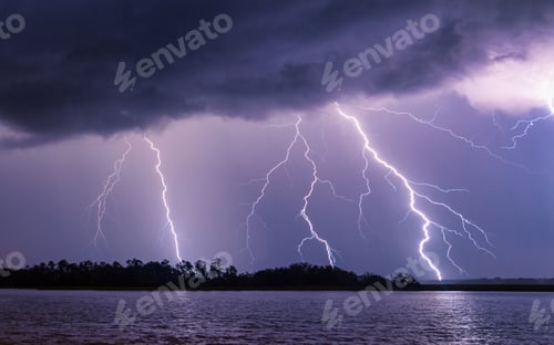 Preview: Mesmerizing shot of multiple lightning strikes by a river with a dark blue sky