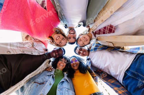 Preview: Smiling portrait of young college student friends in circle looking at camera