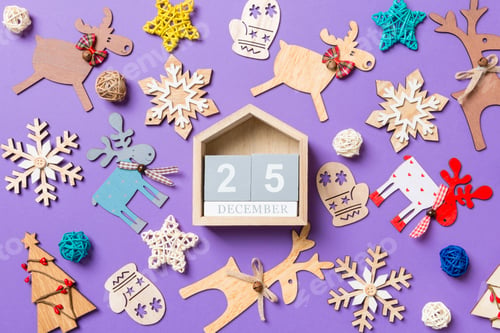 Preview: Festive decorations and toys on purple background. Top view of wooden calendar