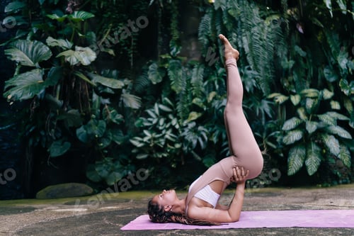 Preview: Flexible woman doing yoga pose during training in green park