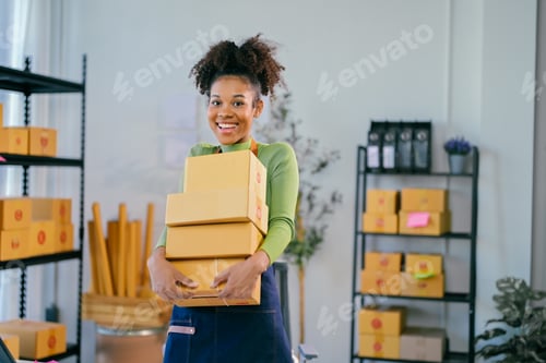 Preview: Smiling African American entrepreneur holding packages in storehouse