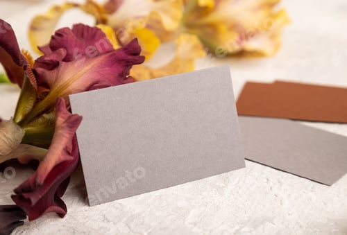 Preview: Gray business card with iris flowers on gray concrete background. side view, copy space.