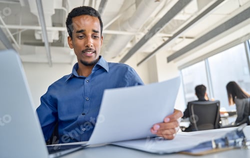 Preview: Busy young African American business man working in office checking papers.