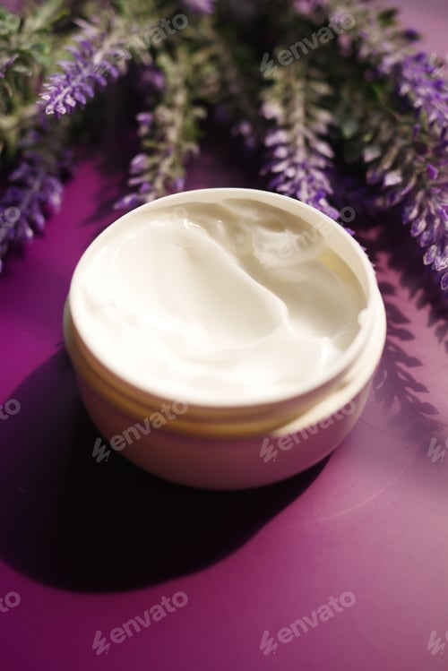 Preview: herbal cream cosmetic in a container and lavender flower on purple background