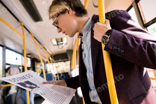 Preview: young businessman in eyeglasses reading newspaper in bus