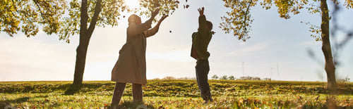 Preview: silhouette of mother and child throwing autumn leaves, park, fall season, having fun, banner