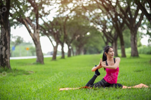 Preview: Young woman practicing yoga in park
