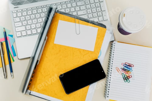 Preview: Top view closeup of a laptop, notebook, smartphone, paper clips and a cup of coffee on the desk