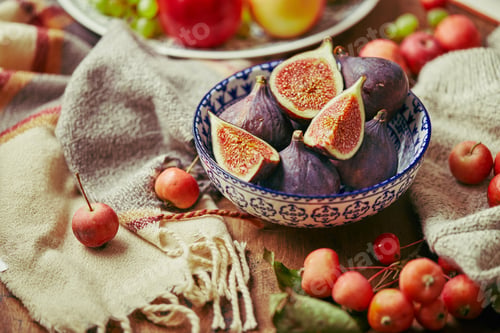 Preview: Dish with figs, apples and grapes with warm cozy knitwear, autumn leaves and apples