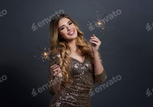 Preview: Portrait of happy woman with burning sparklers at studio shot