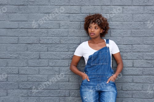 Preview: african woman in dungarees by gray wall