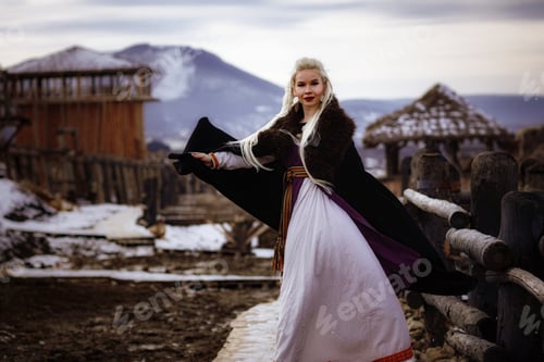 Preview: Beautiful blonde Viking dressed in a black cloak against the backdrop of the castle